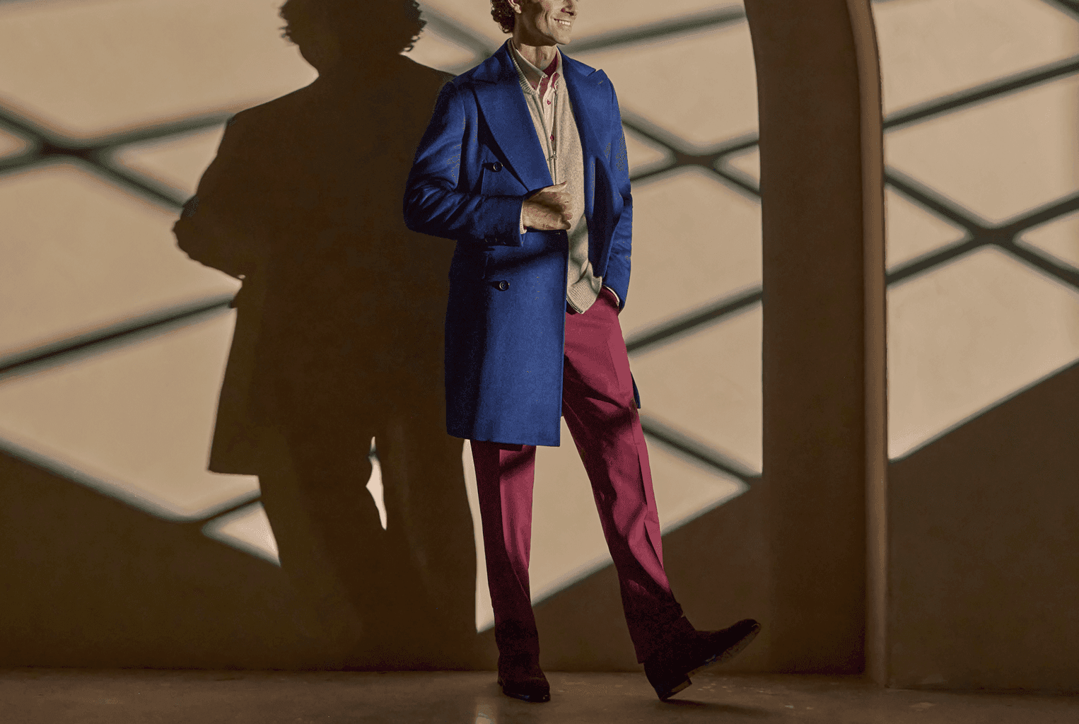 Man walking in a blue overcoat with burgundy trousers.