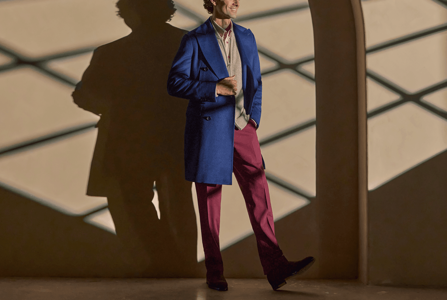 Man walking in a blue overcoat with burgundy trousers.