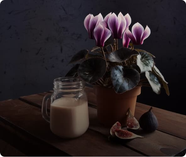 Purple flowers beside a glass of milk and figs on a wooden table.