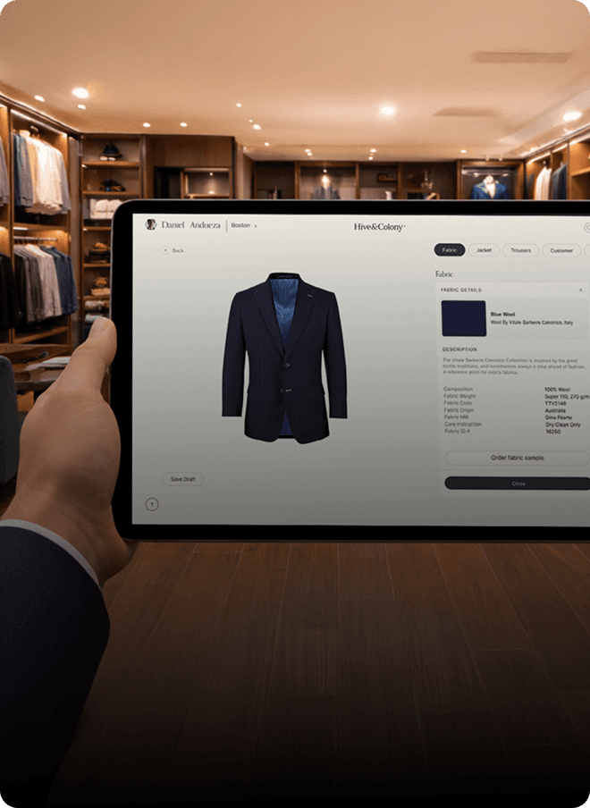 Hand holding a tablet showing a custom jacket in a Hive & Colony showroom.