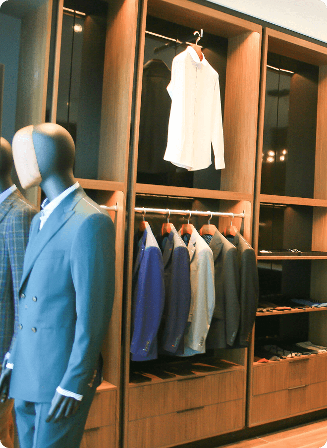 Mannequin in a blue suit beside racks of tailored jackets.