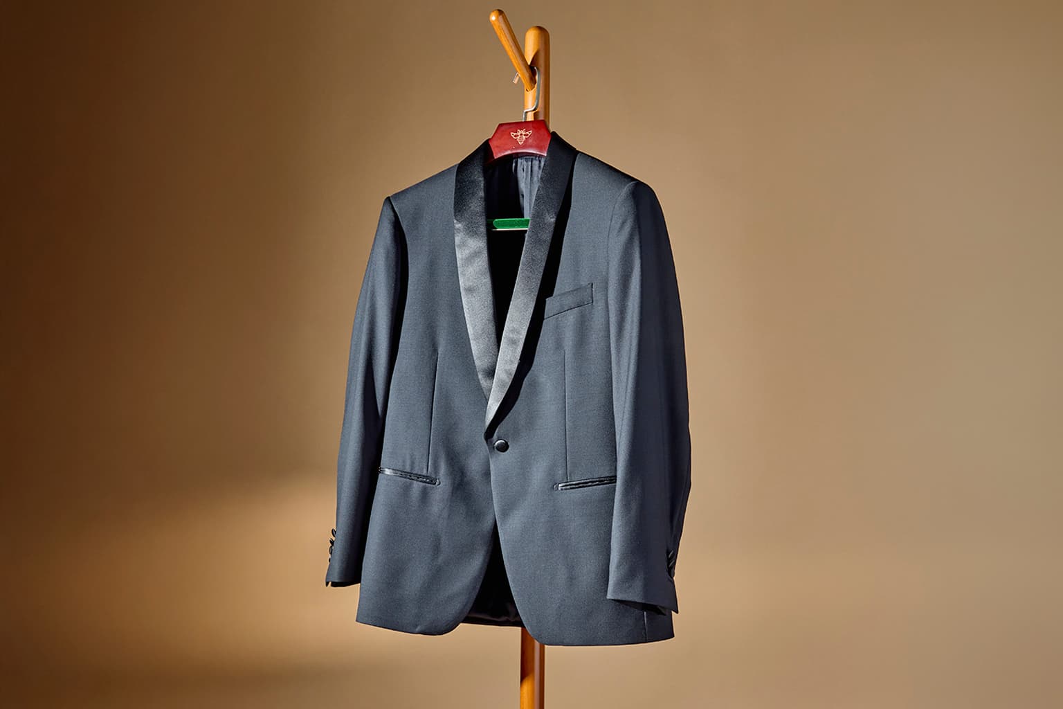 Gray tuxedo jacket hanging on a wooden stand.