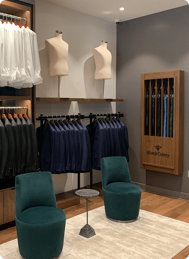 Showroom lounge with green chairs, jacket racks, and an umbrella display.