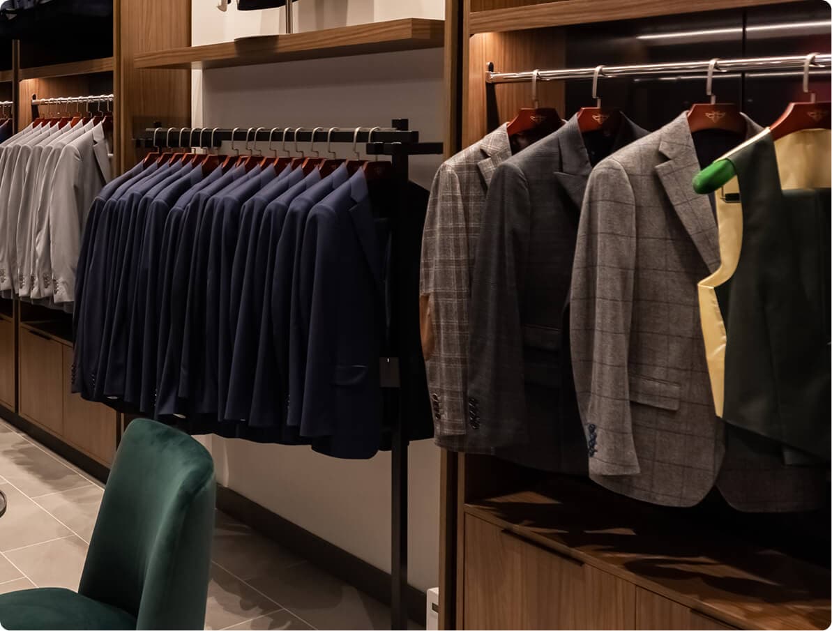 Rack of tailored jackets and shirts inside a Hive & Colony showroom.