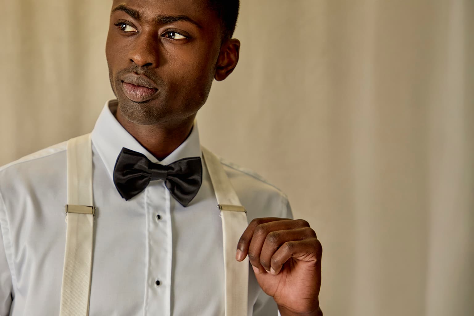 Man wearing formal suspenders with a white shirt and black bow tie.