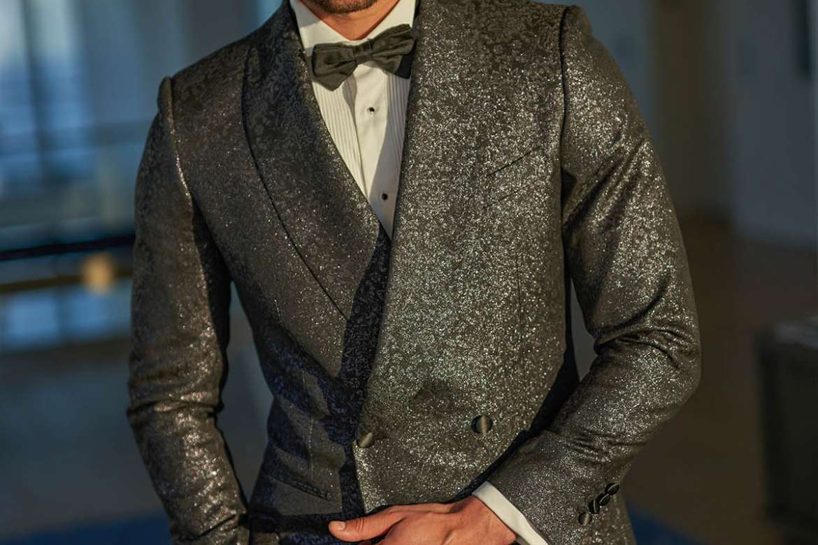 Man wearing a black glitter tuxedo jacket with a bow tie.