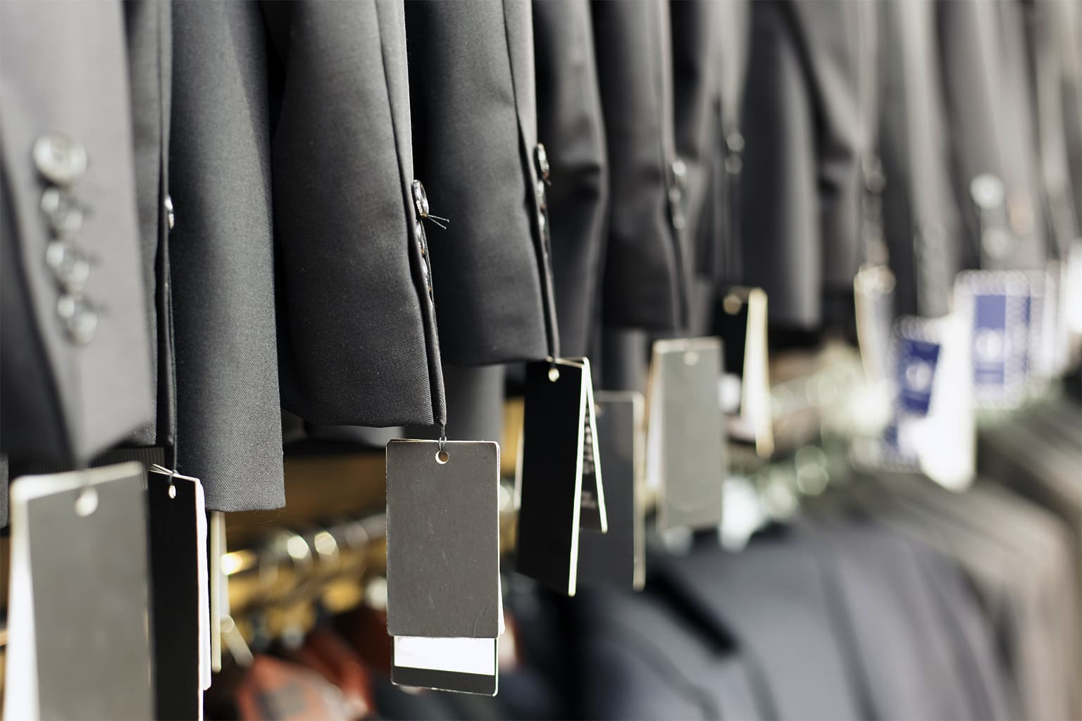 Close-up of black tuxedo jackets hanging on a rack.