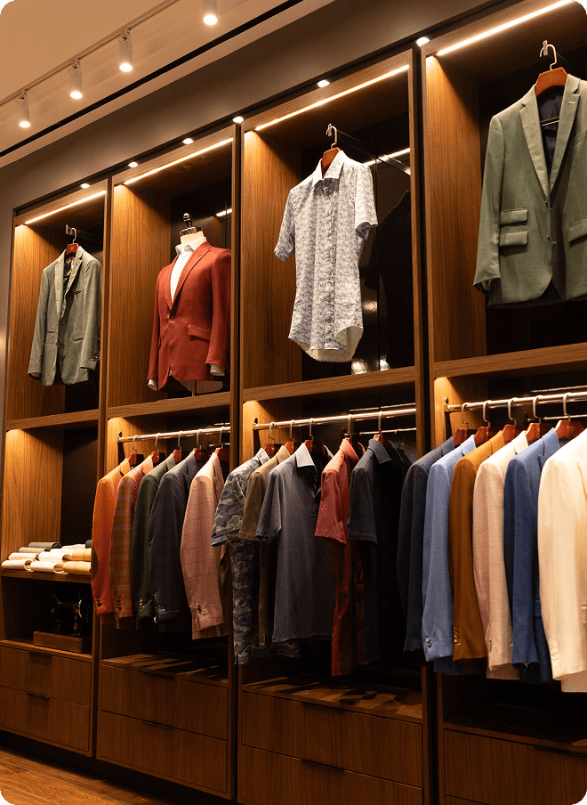 Wooden wardrobe wall displaying jackets, shirts, and tailored garments.