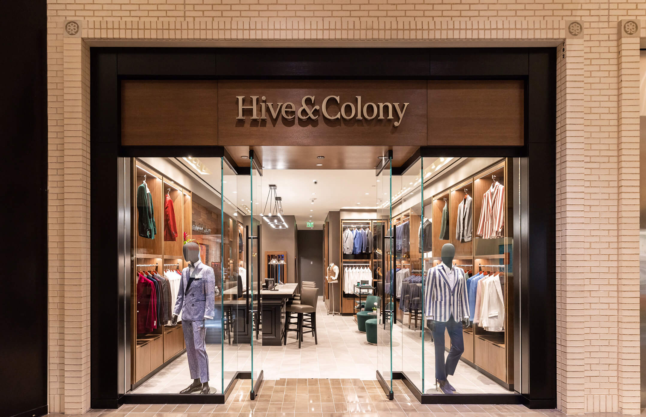 Hive & Colony storefront with mannequins and tailored clothing displays.