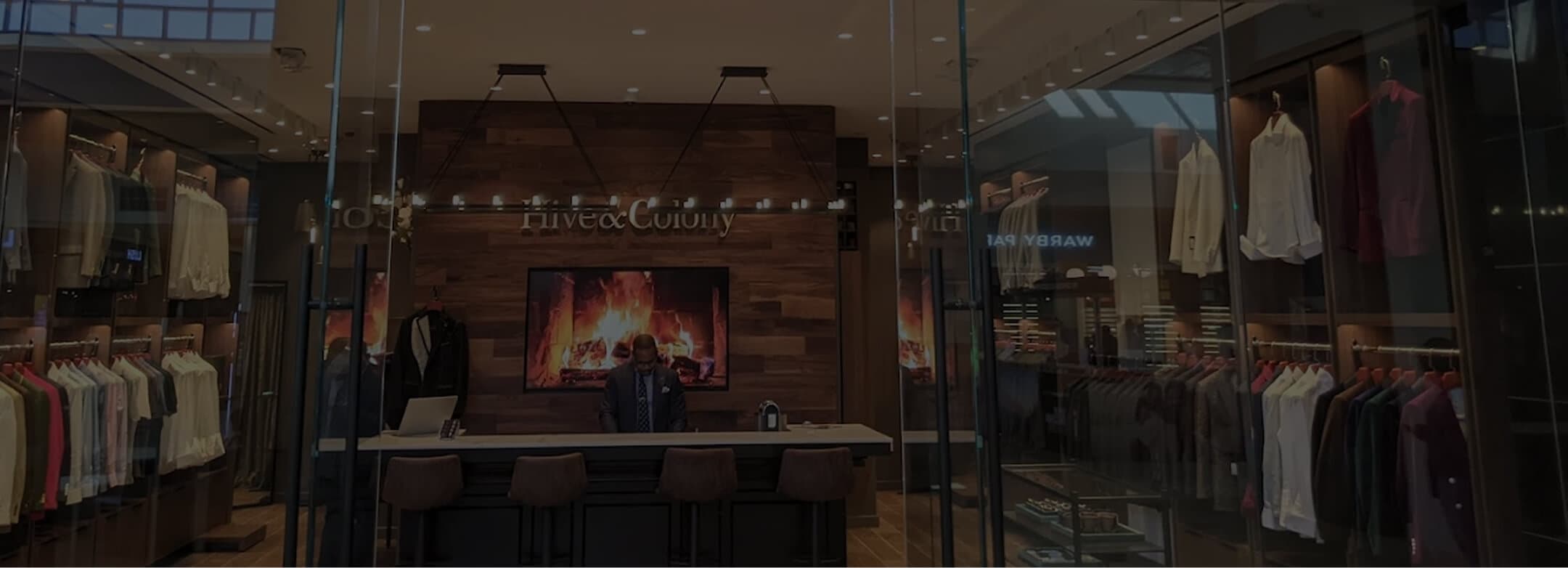 Hive & Colony showroom viewed through glass with clothing displays and fireplace.