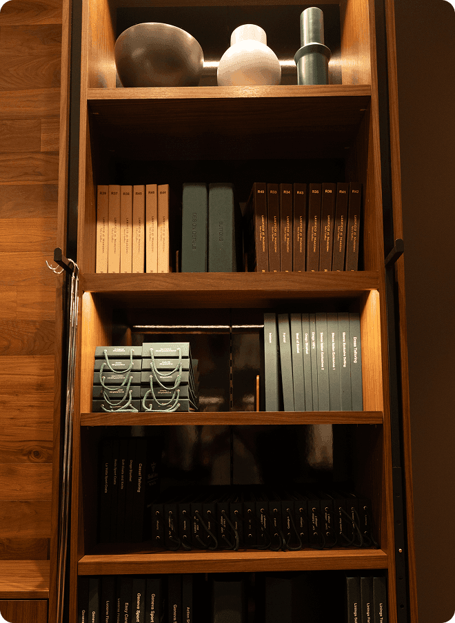 Wooden shelving with tailoring books, fabric samples, and accessories.