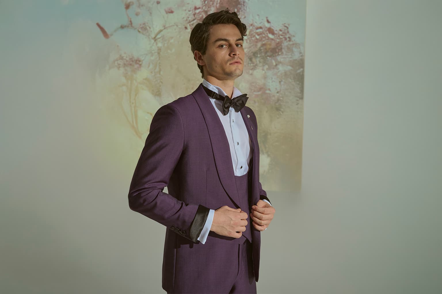Man in a purple tuxedo adjusting his jacket.