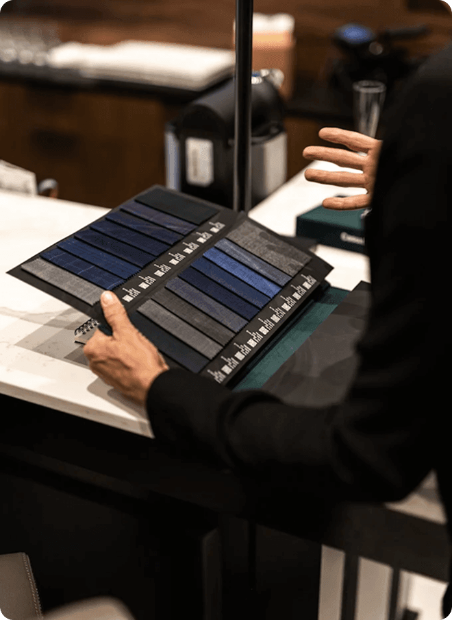 Person presenting blue and gray fabric swatches at a fitting counter.