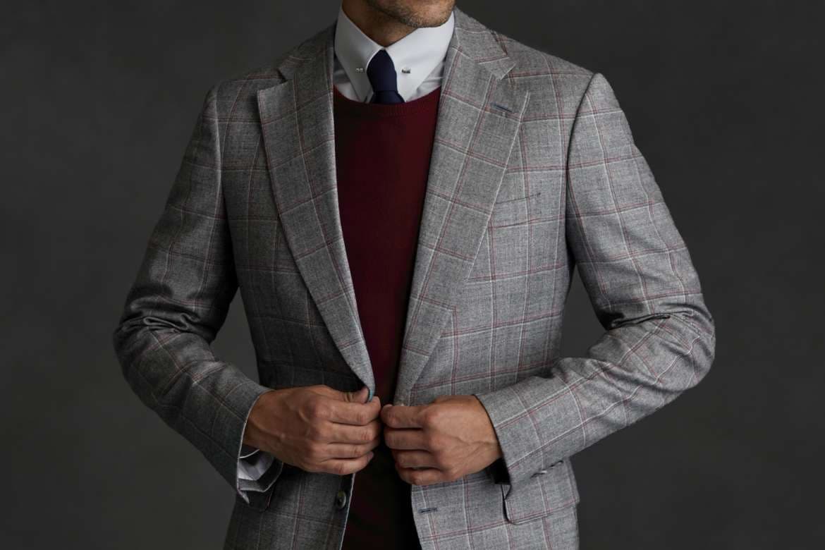 Man in a gray plaid jacket layered over a burgundy sweater and tie.