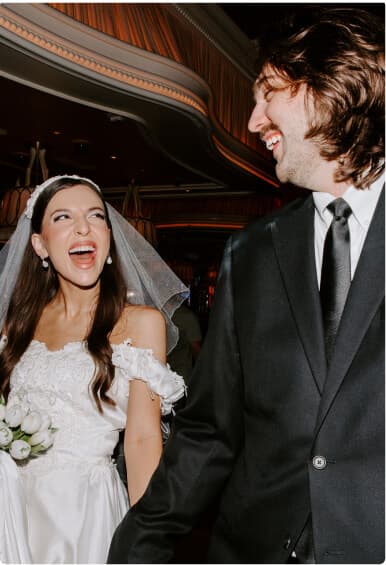 Bride and groom laughing together in wedding attire.