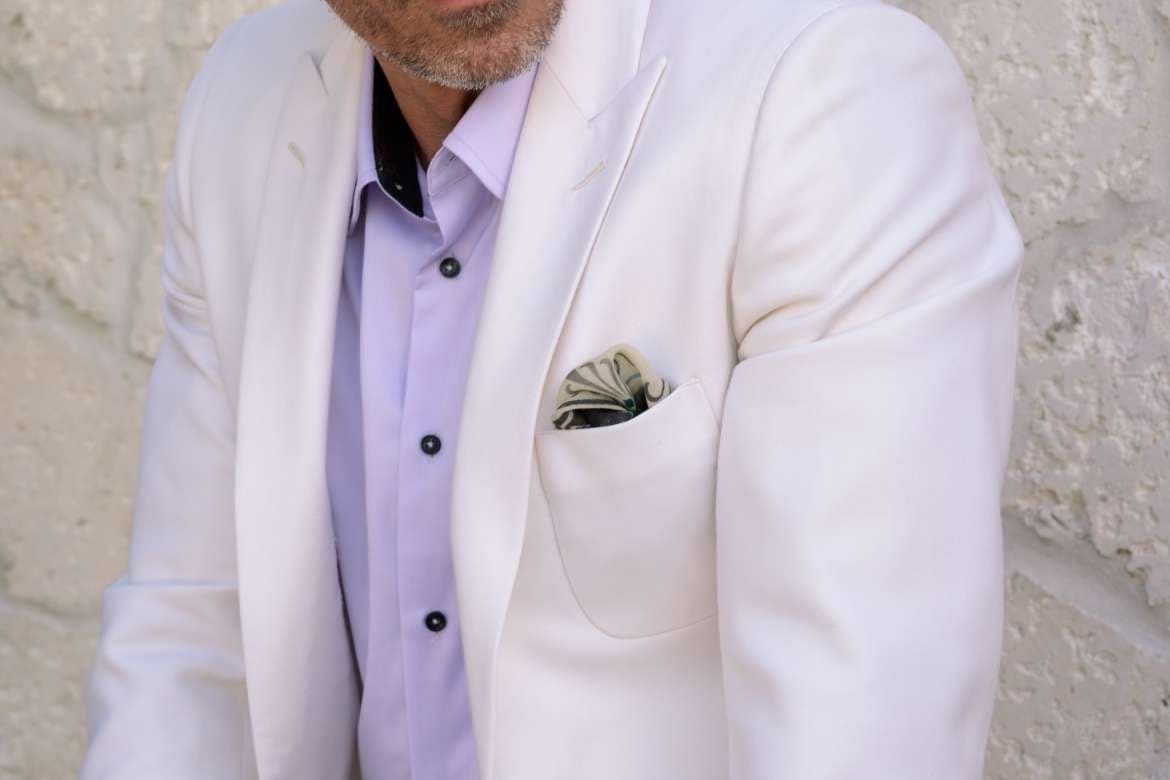 Man in an ivory blazer with a patterned pocket square.
