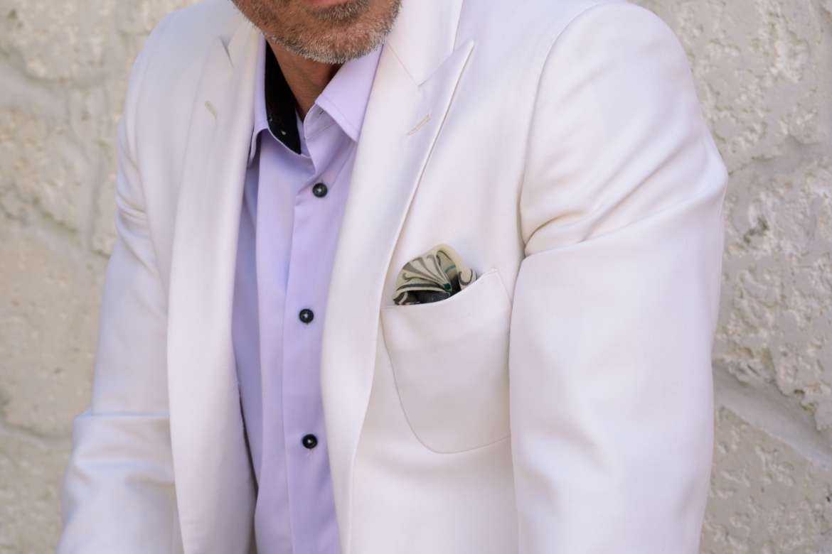 Man in an ivory blazer with a patterned pocket square.