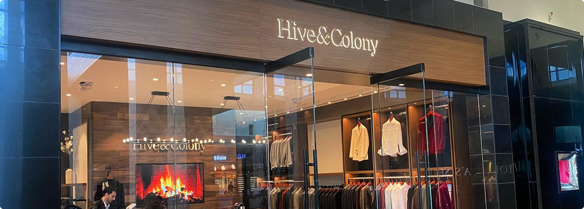 Hive & Colony storefront with suits, shirts, and a fireplace inside.