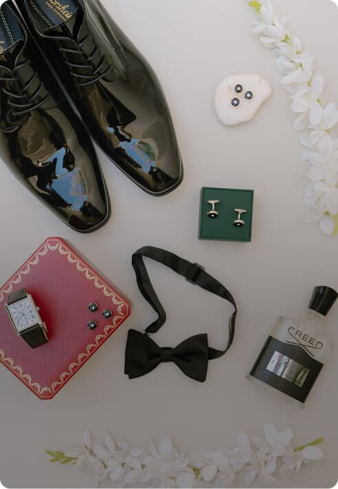 Flat lay of black dress shoes and formal accessories.