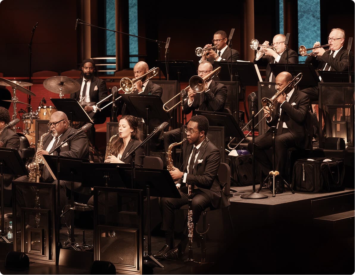 Jazz orchestra performing on stage in formalwear.