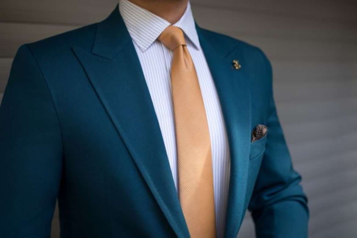 Close-up of a teal suit with a gold tie and pocket square.