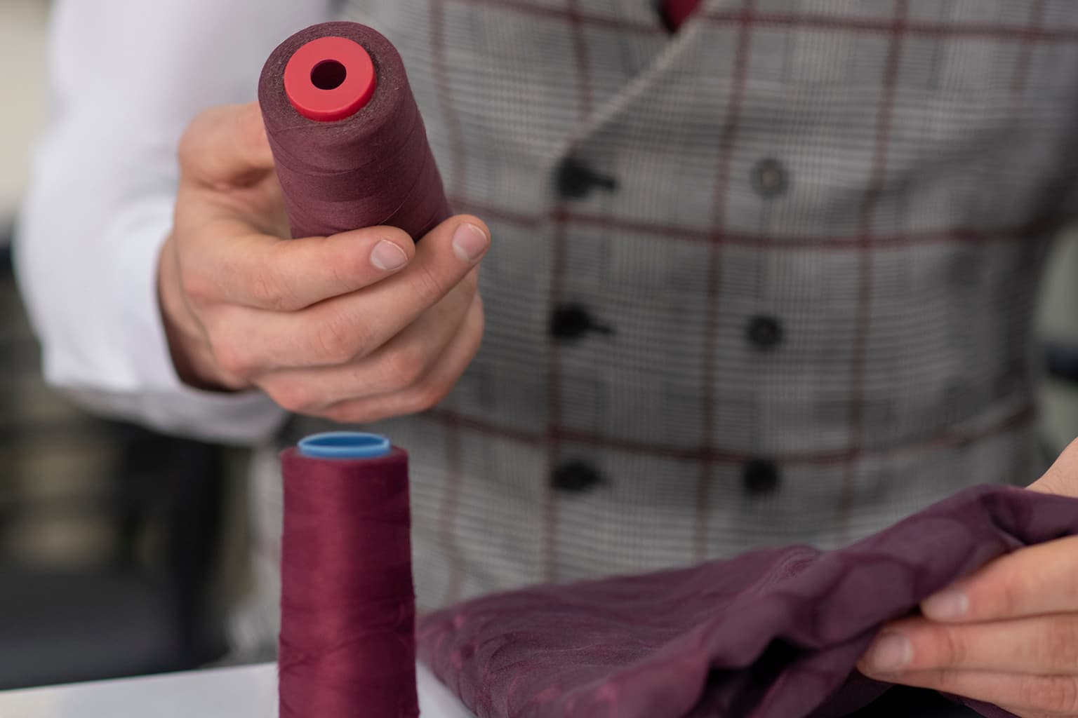 Close-up of burgundy thread spools and matching fabric.