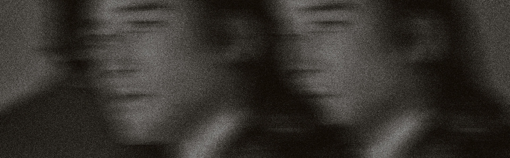 Blurred black-and-white portrait of two figures in suits.